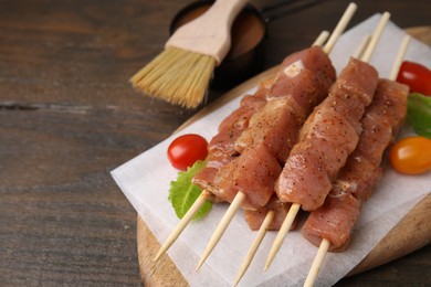 Photo of Skewers with cut raw marinated meat on wooden table. Space for text