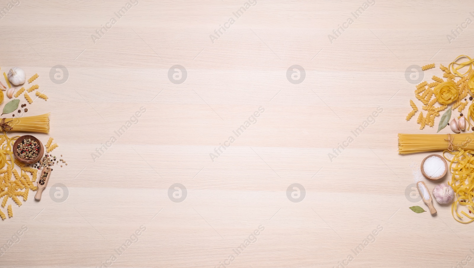 Photo of Flat lay composition with different types of pasta on light wooden table, space or text