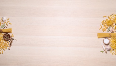 Photo of Flat lay composition with different types of pasta on light wooden table, space or text