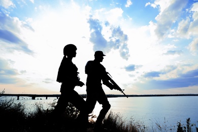 Photo of Soldiers in uniform patrolling outdoors. Military service