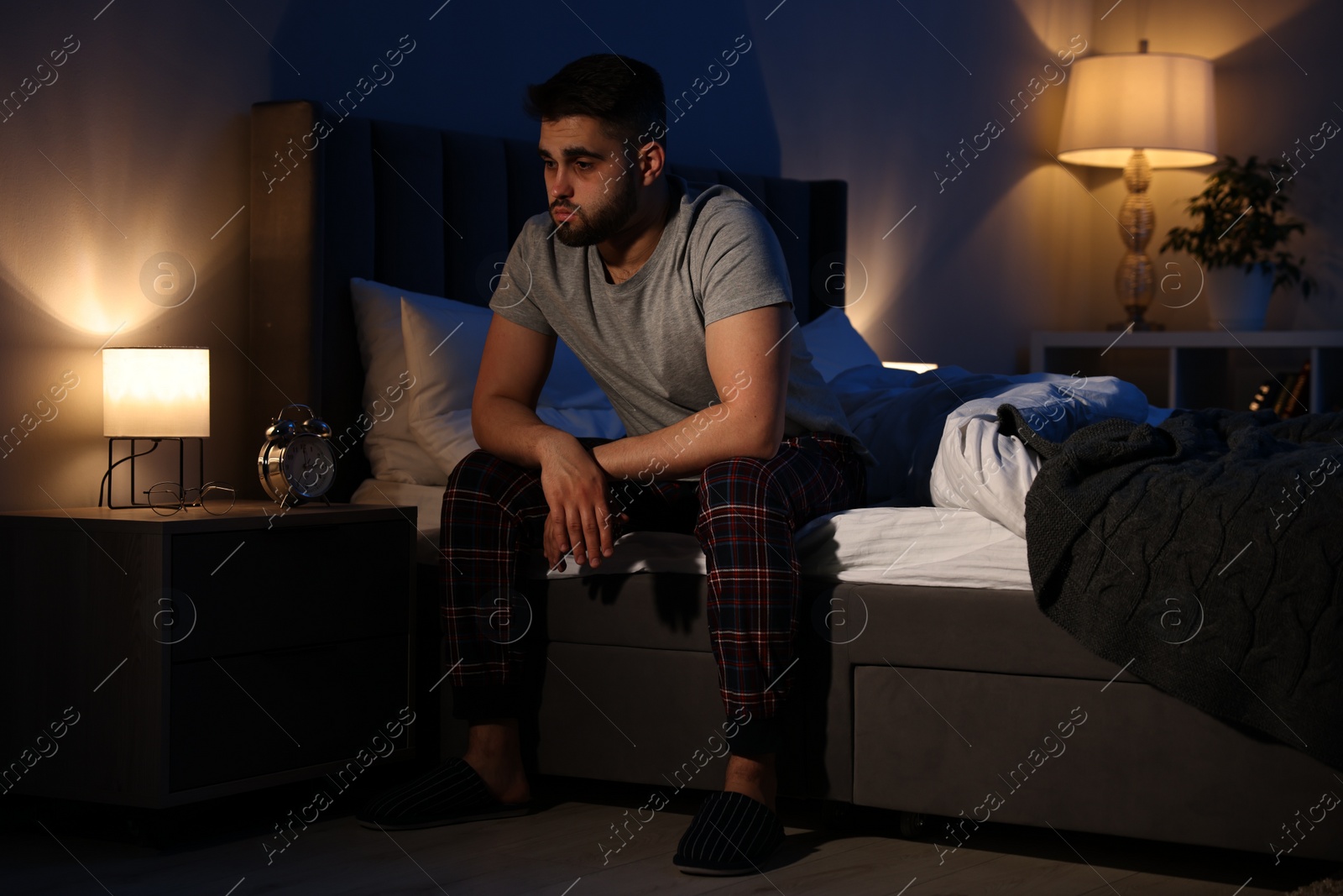 Photo of Frustrated man suffering from insomnia on bed