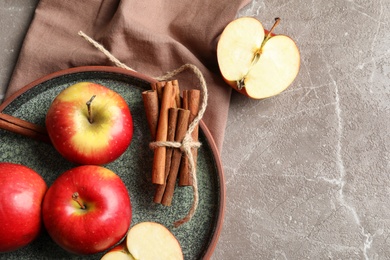 Fresh apples and cinnamon sticks on table, top view