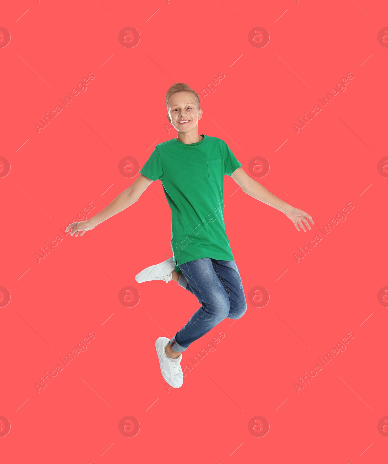 Image of Teenage boy jumping on red background, full length portrait