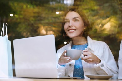 Special Promotion. Happy young woman with cup of drink using laptop in cafe, view from outdoors