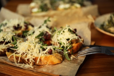 Delicious bruschettas with beef and cheese on wooden table, closeup