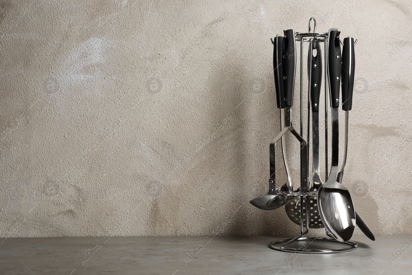 Photo of Holder with clean kitchen utensils on table. Space for text