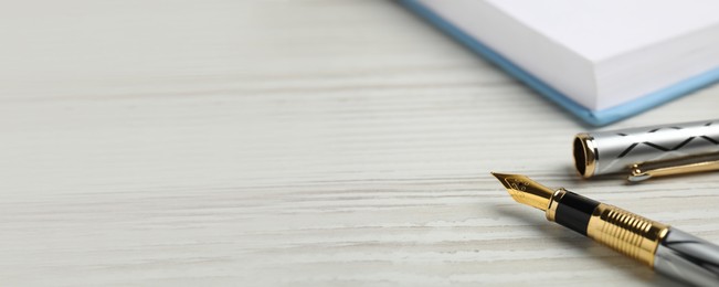 Image of Beautiful fountain pen with ornate nib on white wooden table, closeup view with space for text. Banner design