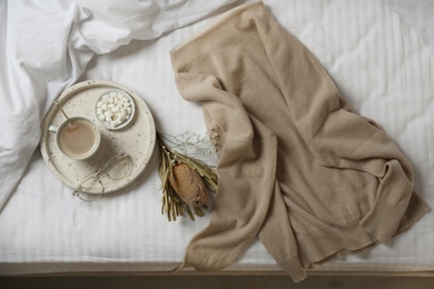 Photo of Flat lay composition with soft cashmere sweater on bed at home