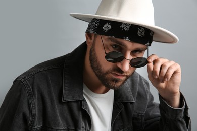 Fashionable young man in stylish outfit with bandana on grey background