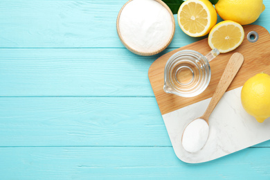 Photo of Baking soda, vinegar and cut lemons on light blue wooden table, flat lay. Space for text