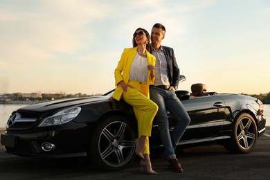 Stylish couple near luxury convertible car outdoors