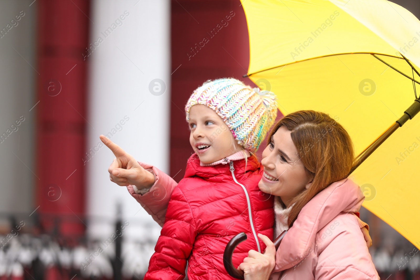 Photo of Mother and daughter with umbrella in city on autumn rainy day