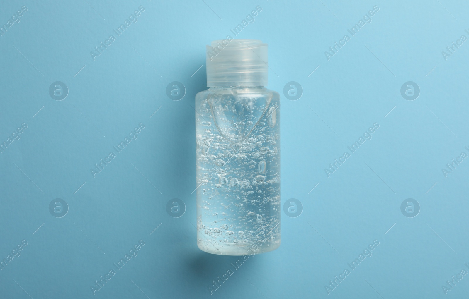 Photo of Bottle of cosmetic gel on light blue background, top view