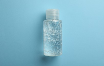 Photo of Bottle of cosmetic gel on light blue background, top view