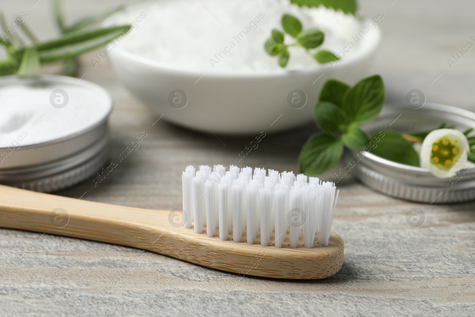 Photo of Toothbrush, sea salt and green herbs on wooden table, closeup