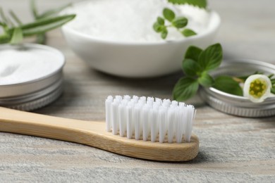Photo of Toothbrush, sea salt and green herbs on wooden table, closeup
