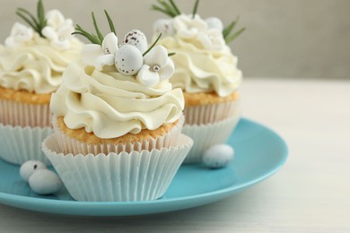 Photo of Tasty Easter cupcakes with vanilla cream on light wooden table, closeup