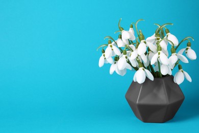 Photo of Beautiful snowdrops in vase on light blue background, space for text