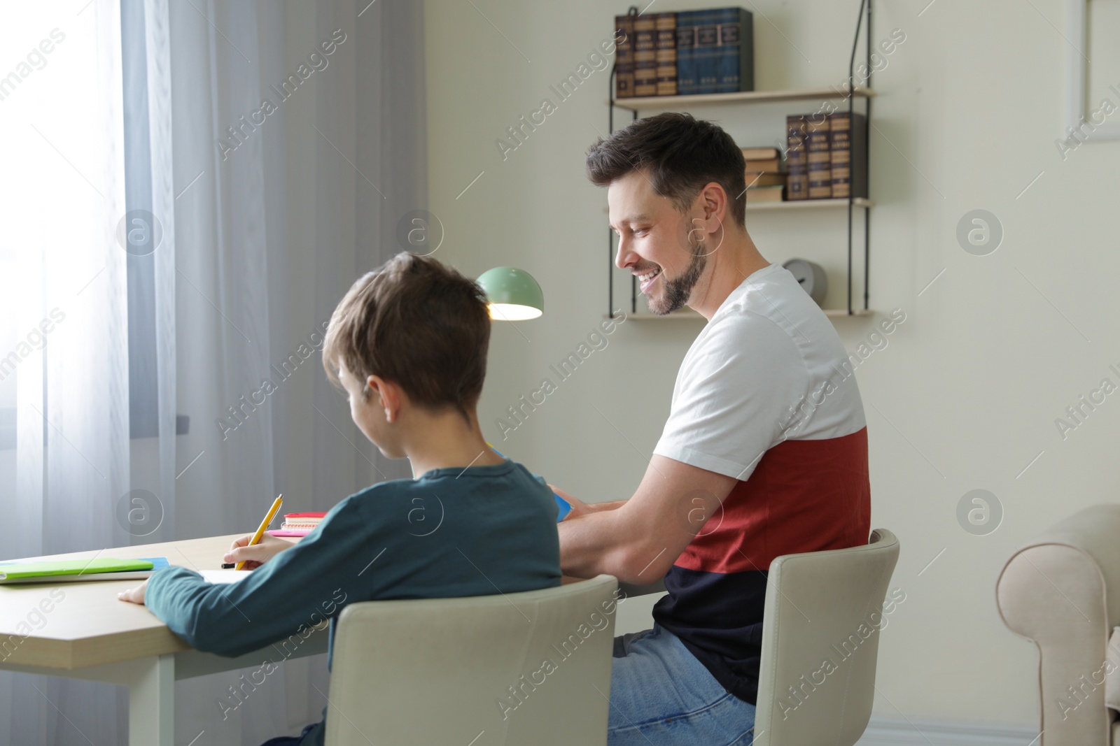 Photo of Dad helping his son with school assignment at home