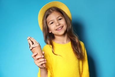 Photo of Adorable little girl with delicious ice cream against color background