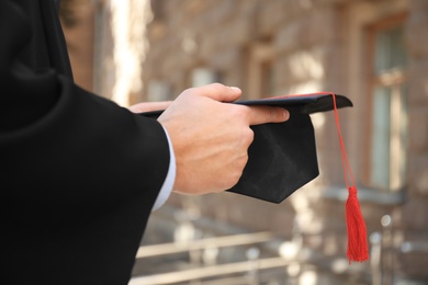 Photo of Student with graduation hat outdoors on sunny day, closeup