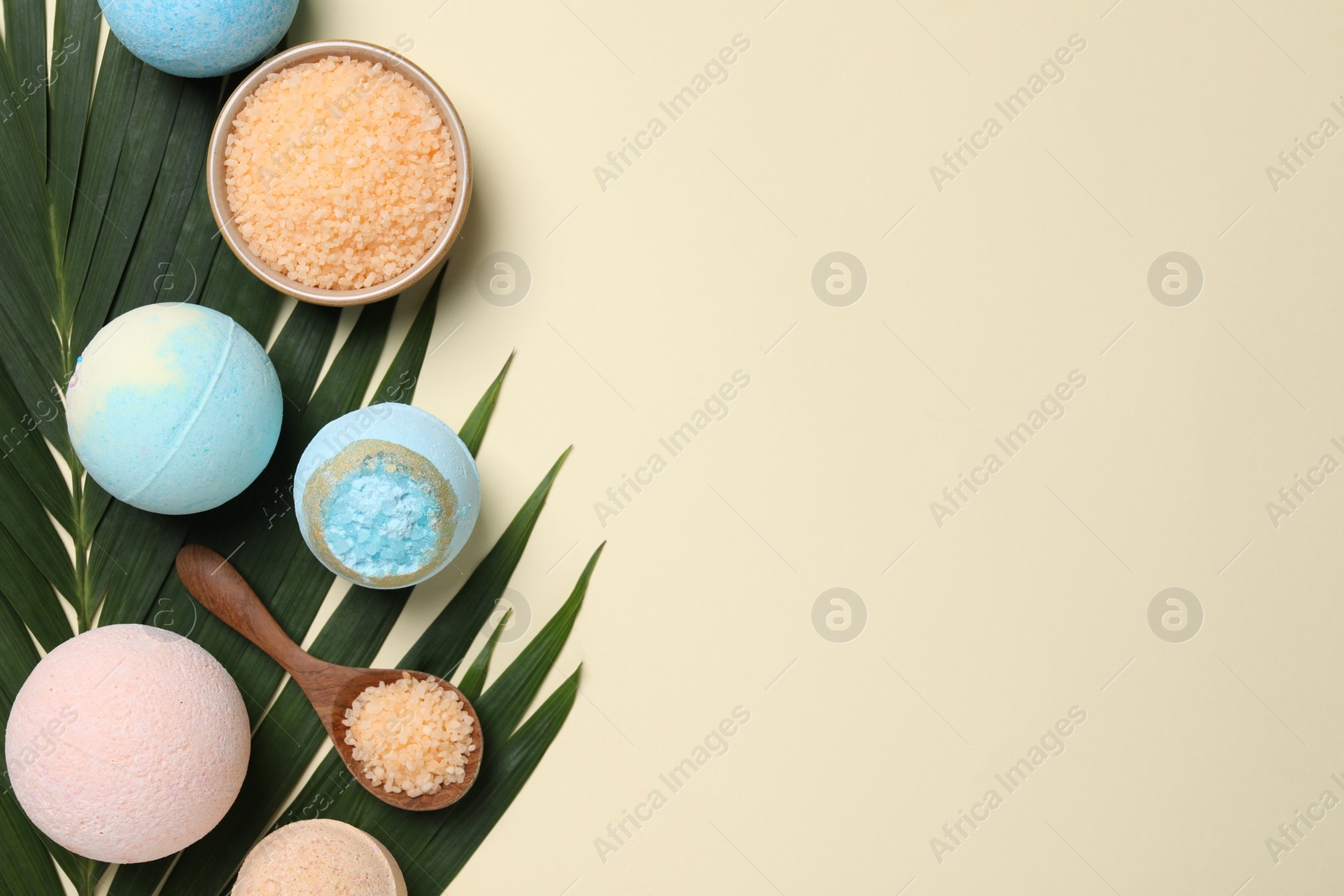 Photo of Bath bombs, green leaf and sea salt on beige background, flat lay. Space for text