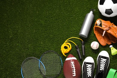 Photo of Different sports equipment on green grass, flat lay. Space for text