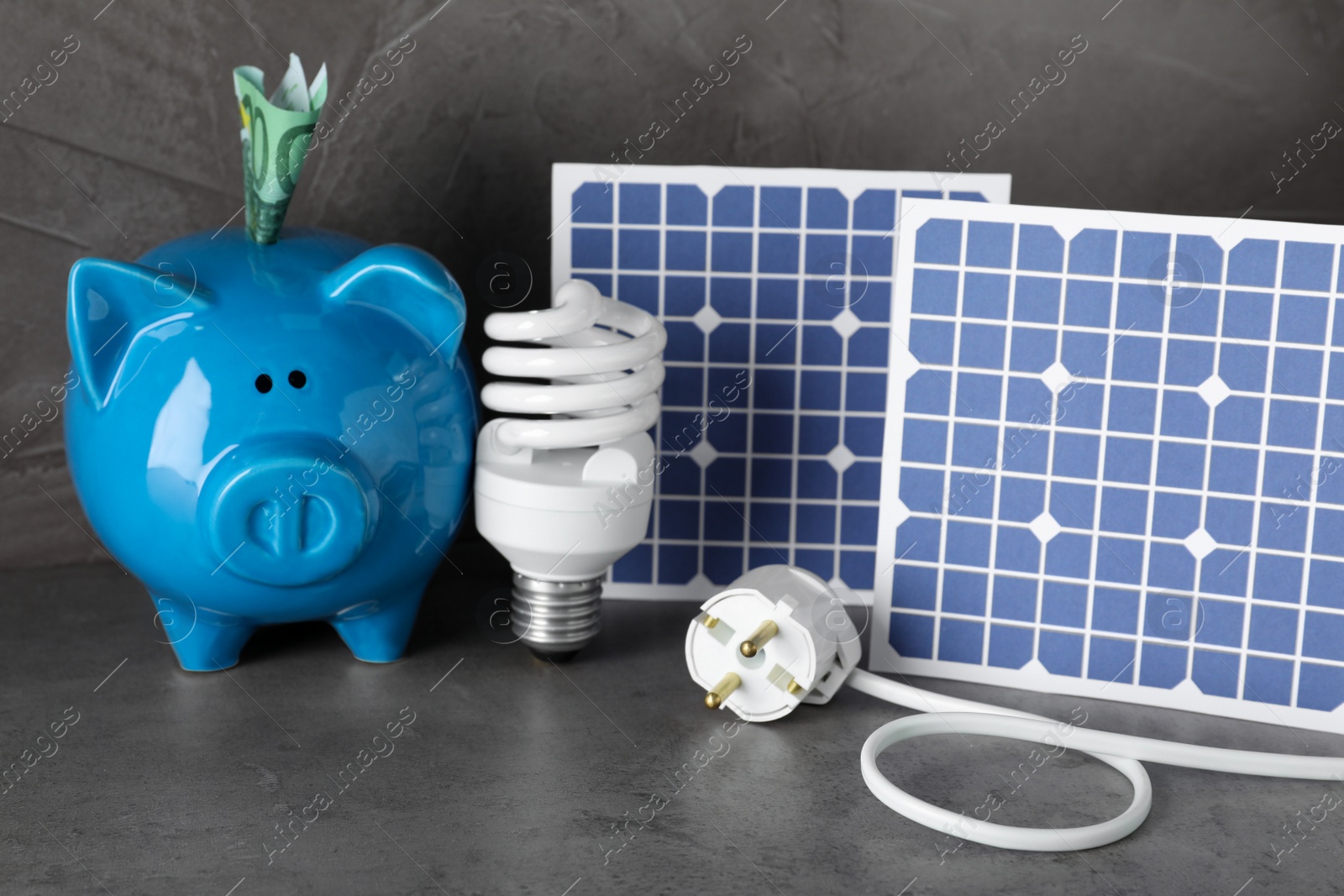 Photo of Composition with solar panels and piggy bank on grey stone table