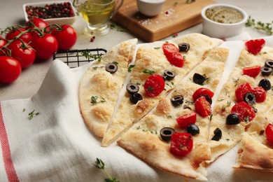 Photo of Focaccia bread with olives and tomatoes on table, closeup