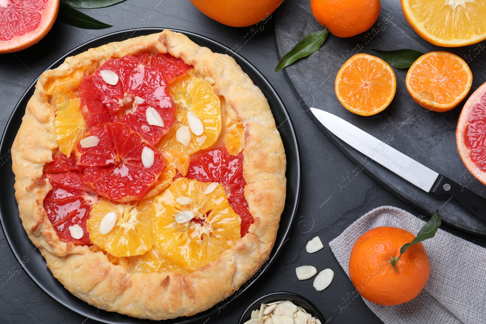 Photo of Tasty galette with citrus fruits served on grey table, flat lay