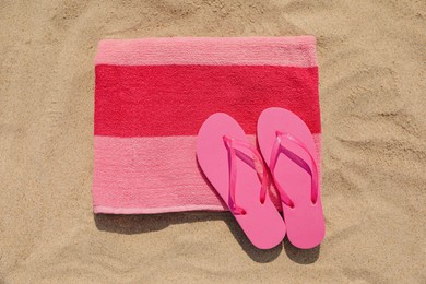 Photo of Beach towel with slippers on sand, top view