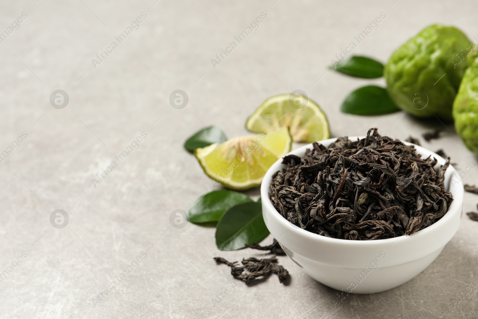 Photo of Dry bergamot tea leaves and fresh fruits on light grey table, space for text