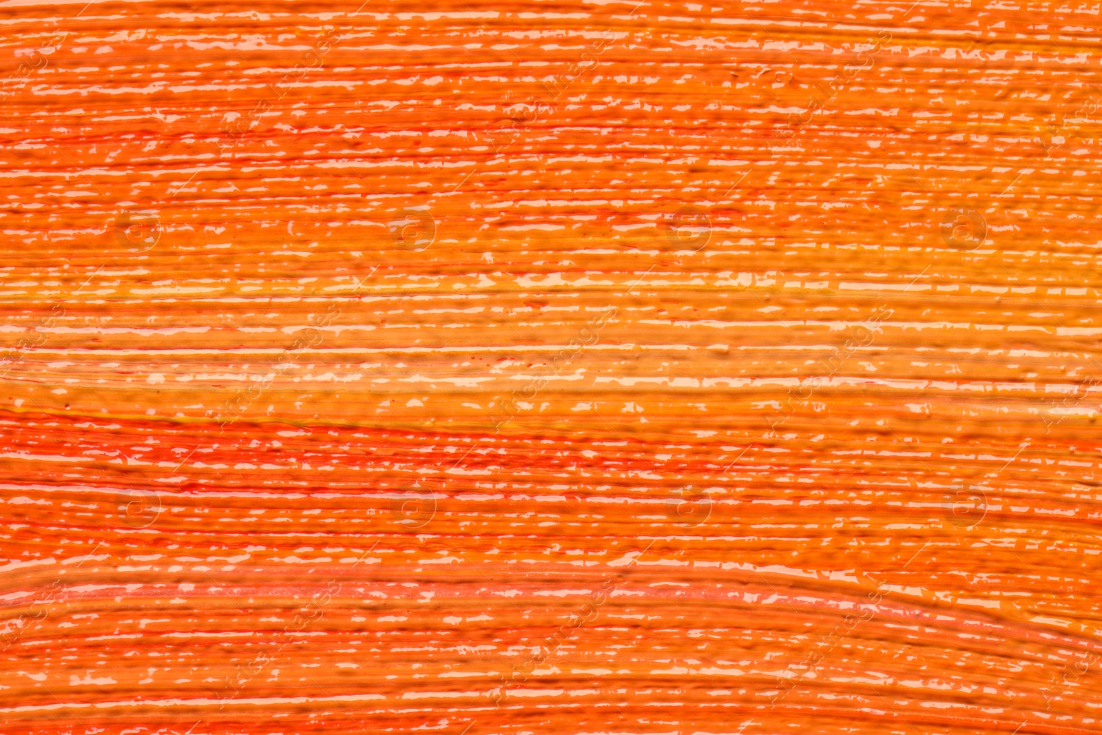 Photo of Beautiful strokes of orange oil paints as background, closeup