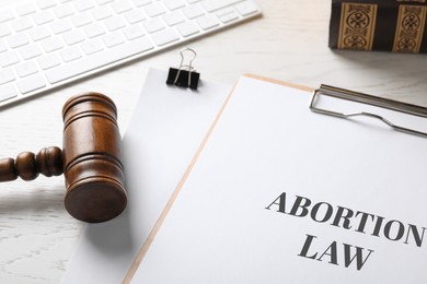 Image of Clipboard with text Abortion Law and gavel on white wooden table, closeup