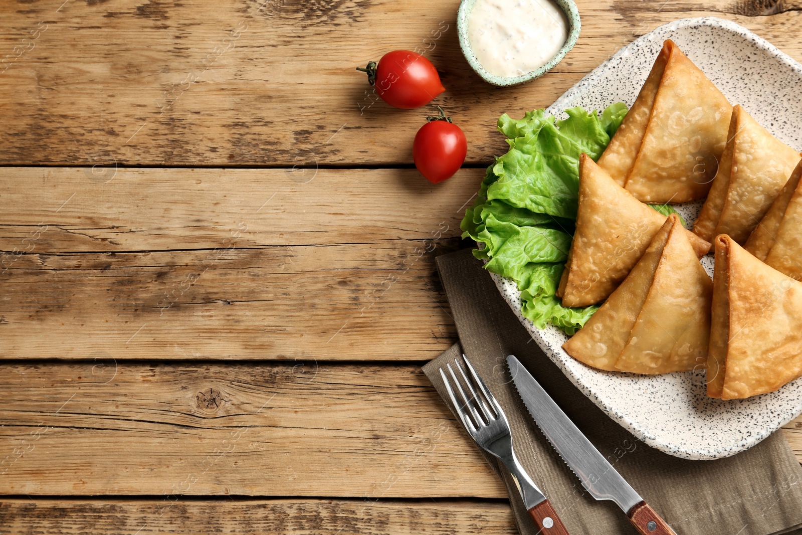 Photo of Fresh delicious crispy samosas served on wooden table, flat lay. Space for text