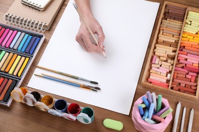 Photo of Artist drawing picture with pastel pencil at wooden table, closeup