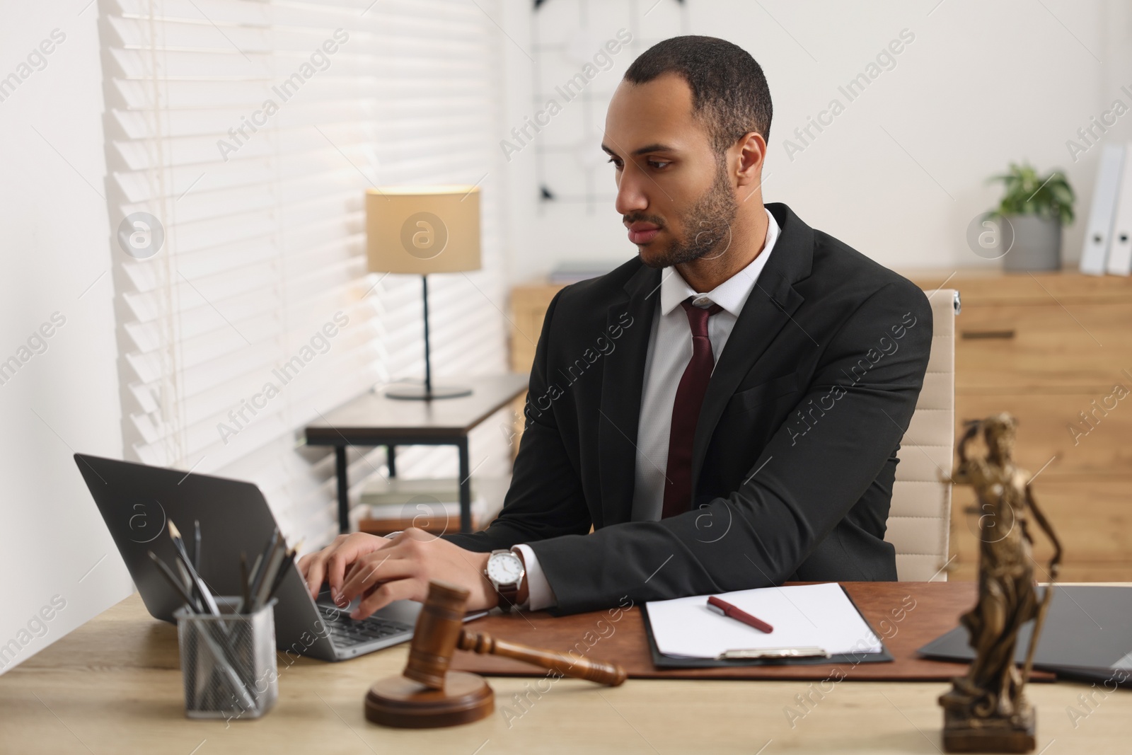 Photo of Serious lawyer working with laptop at table in office