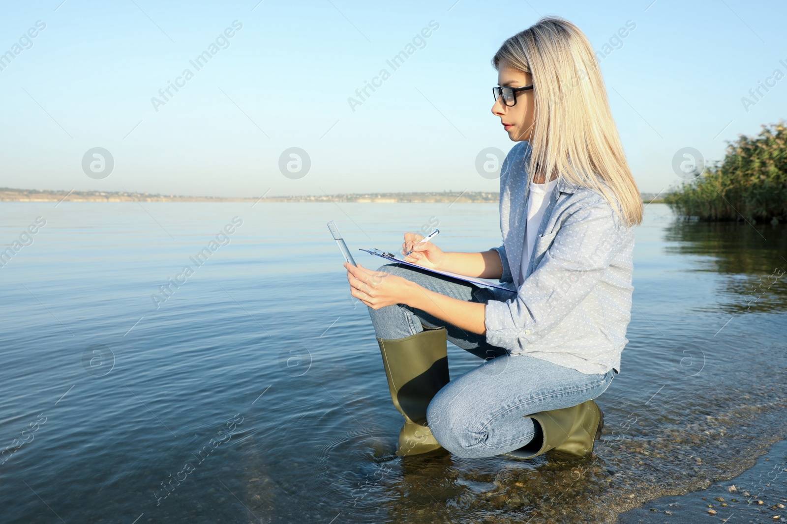 Photo of Scientist with clipboard and sample taken from river