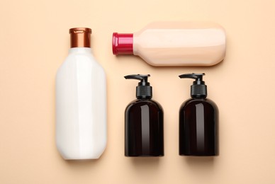 Bottles of shampoo on beige background, flat lay
