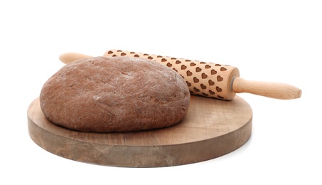 Wooden board with raw rye dough and rolling pin on white background