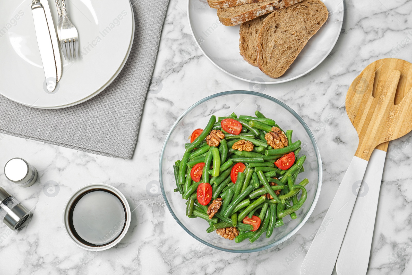 Photo of Tasty green beans with tomatoes served for dinner on marble table, top view