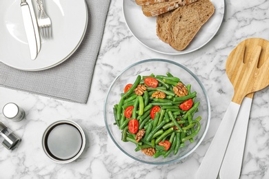 Photo of Tasty green beans with tomatoes served for dinner on marble table, top view