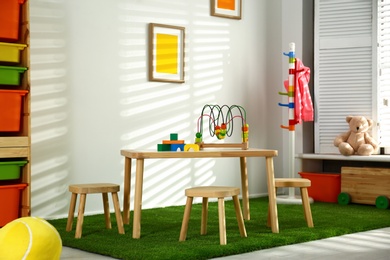 Photo of Stylish playroom interior with wooden table and stools