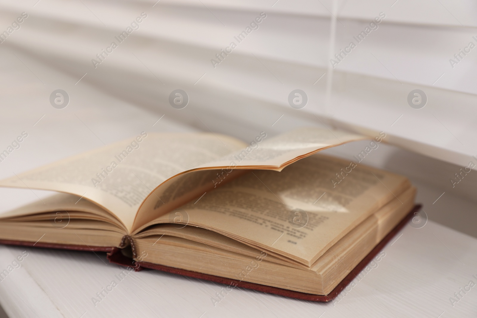 Photo of Open hardcover book on window sill indoors