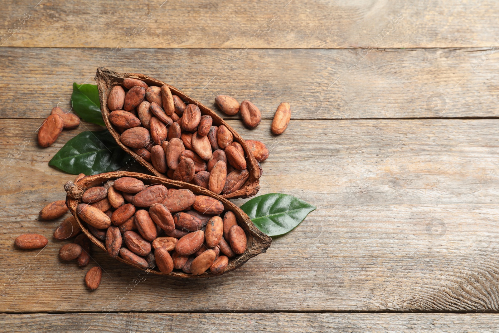 Photo of Cocoa pods and beans on wooden table, space for text