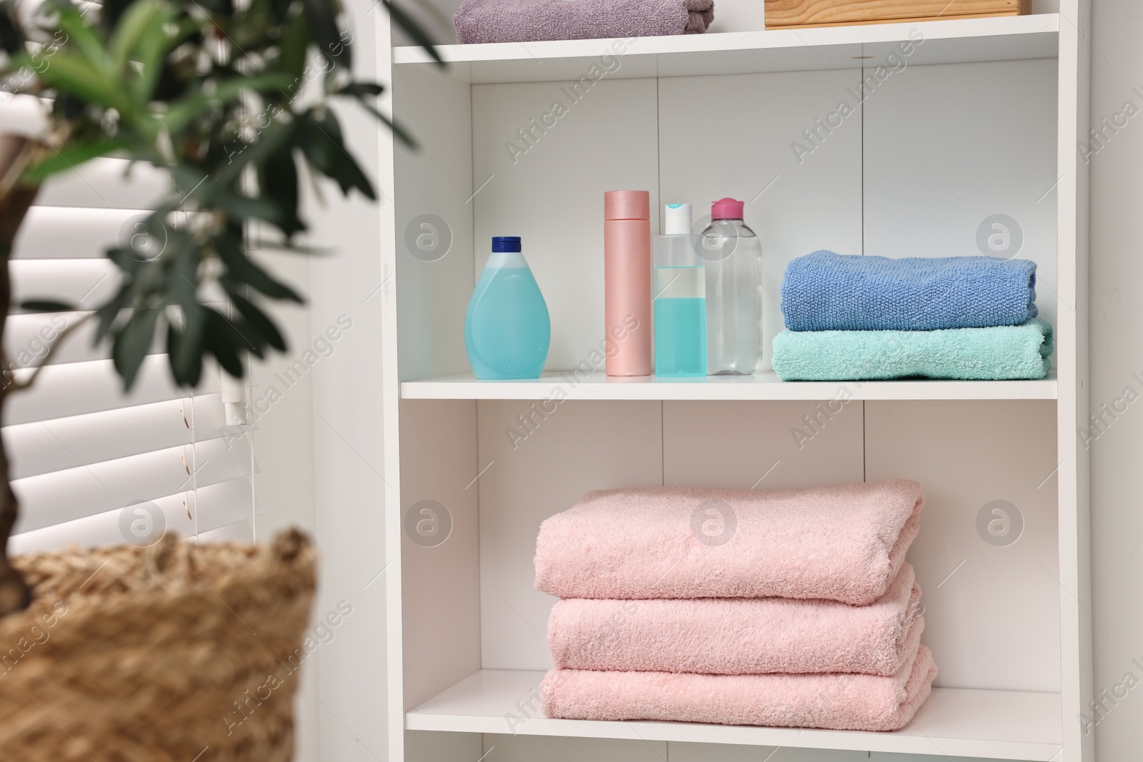 Photo of Shelving unit with clean towels and toiletries indoors