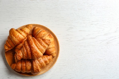 Photo of Plate with tasty croissants and space for text on white wooden background, top view. French pastry