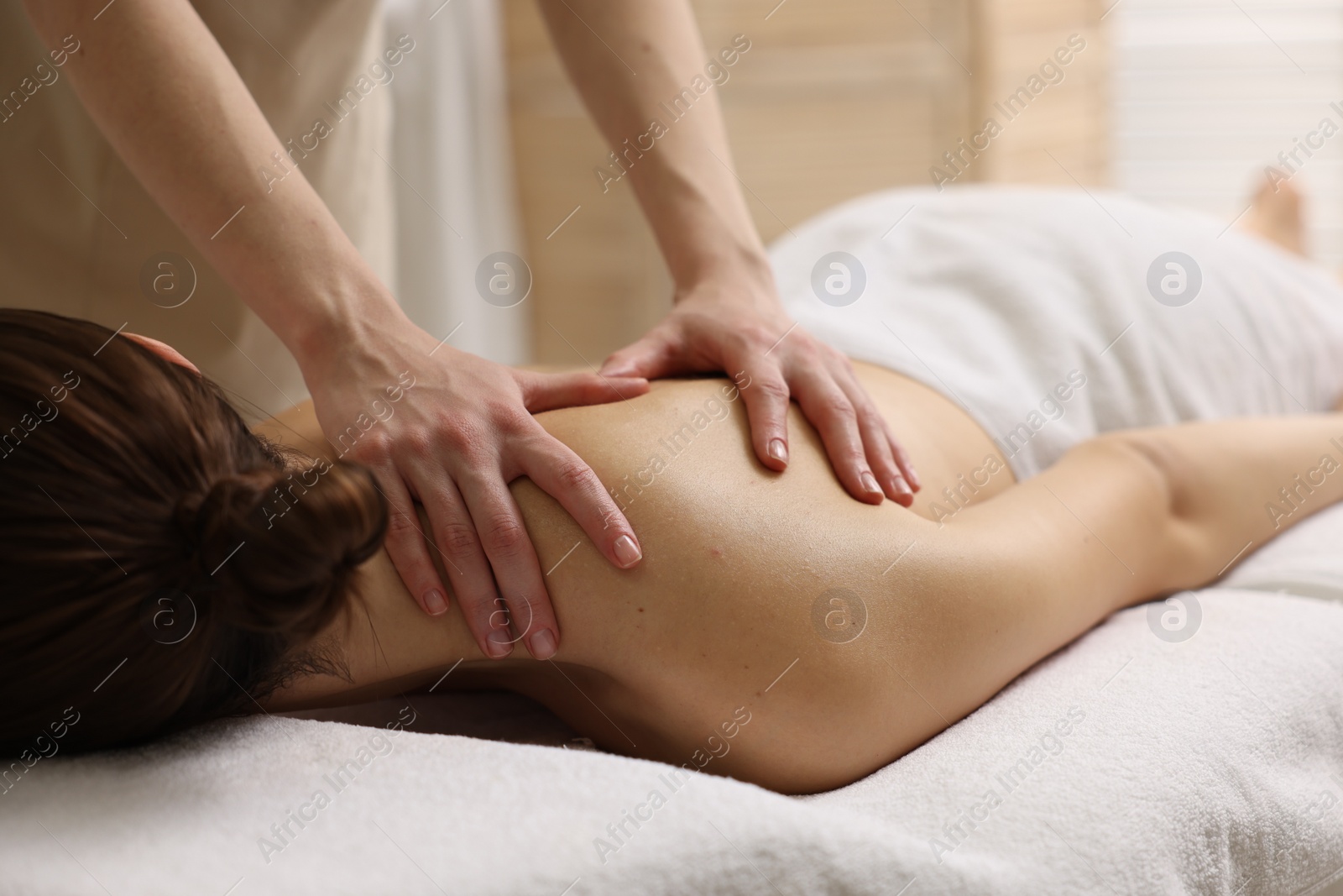 Photo of Woman receiving back massage on couch in spa salon