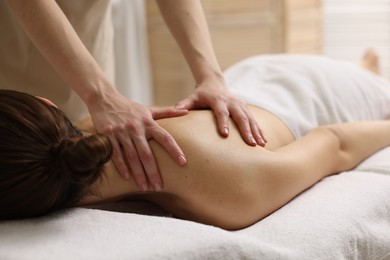 Photo of Woman receiving back massage on couch in spa salon