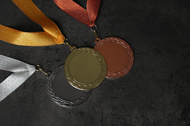 Photo of Gold, silver and bronze medals on grey stone background, flat lay. Space for design